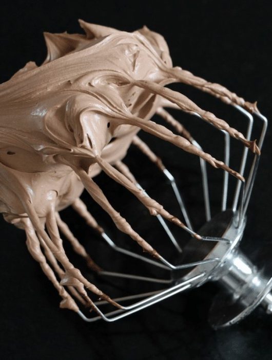 Fouet recouvert de ganache montée chocolat onctueuse et brillante sur fond noir