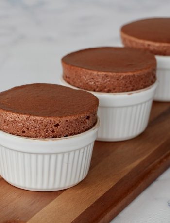 Soufflé au chocolat doré, trois ramequins alignés sur une planche en bois