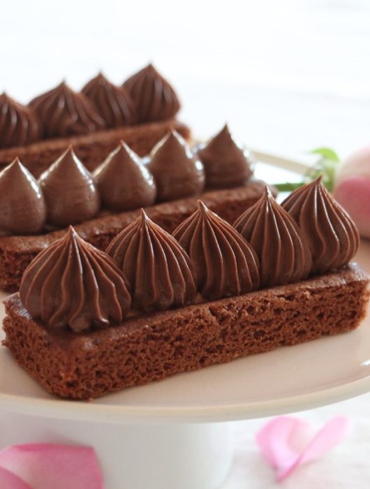Crèmeux chocolat dressé sur biscuits rectangulaires avec roses roses en arrière-plan