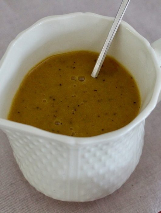Purée de passion dorée dans une cruche blanche texturée avec cuillère argentée