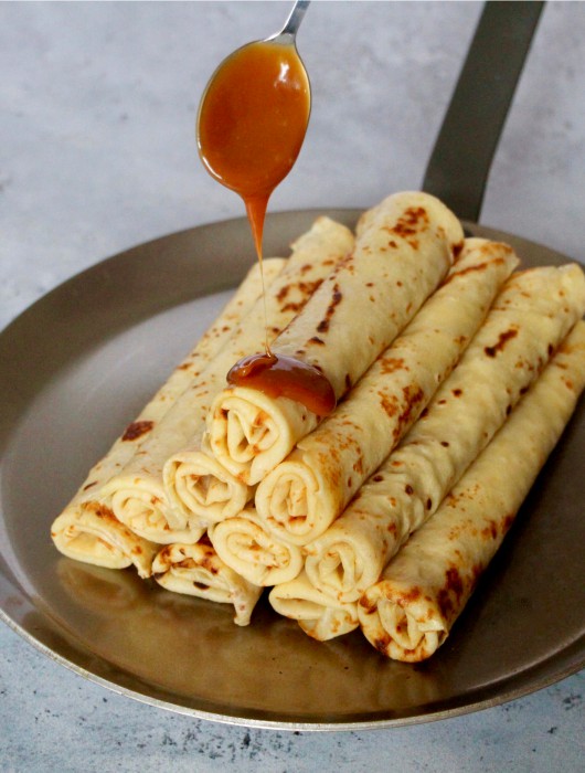 Crêpes roulées sur assiette, nappées de caramel, mettant en valeur la crepe paul bocuse