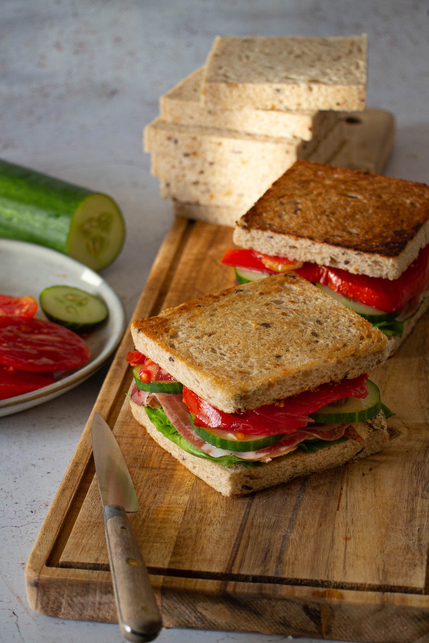 Chicken sandwich with cucumbers and tomatoes on a wooden board