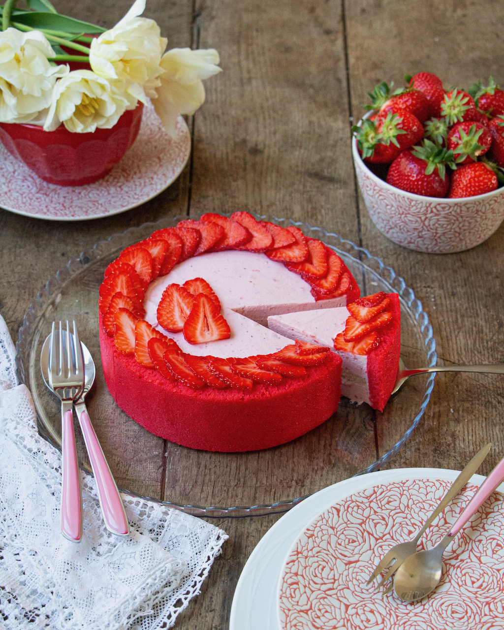 Sliced strawberry Bavarian cream, decorated with fresh strawberries, on a rustic wooden table
