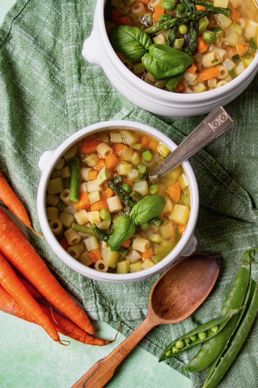 Bowl of colorful minestrone with asparagus and basil, a perfect spring dish for friends