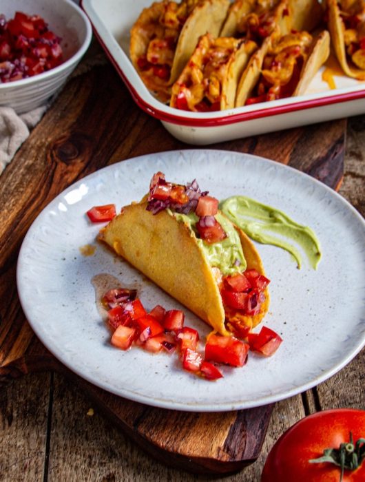 Taco mexicain garni de poulet, avocat crémeux et dés de tomate rouge
