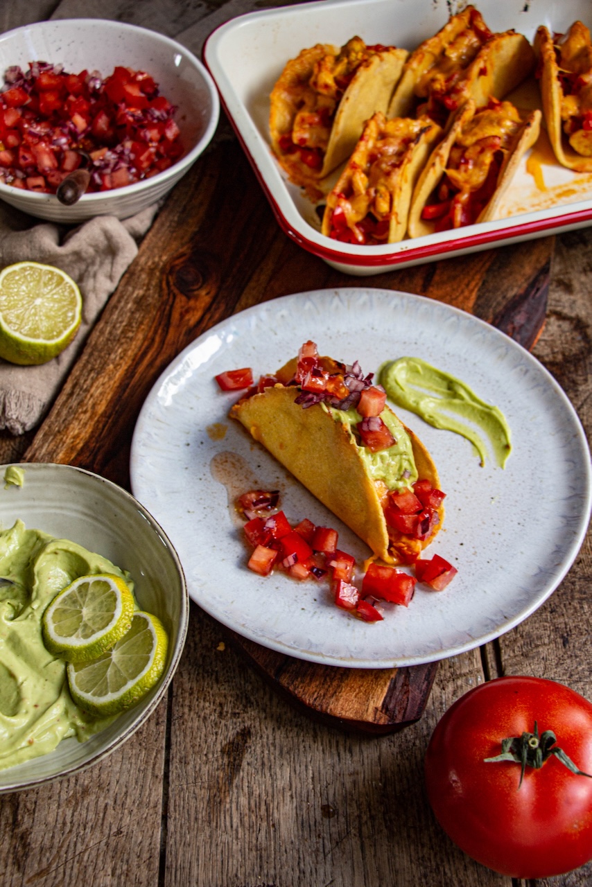 A taco filled with chicken, avocado, and salsa on a white plate
