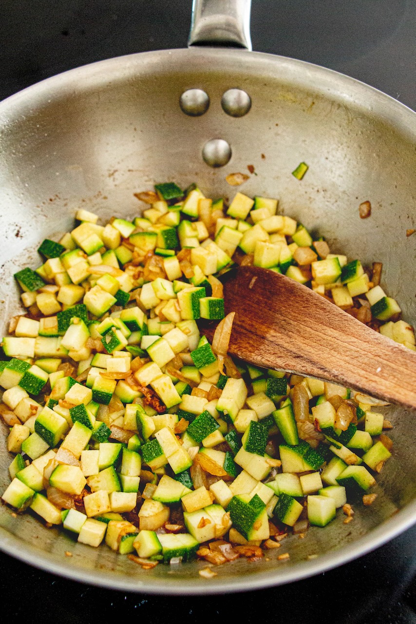 Diced zucchini sautéing in a skillet, key step in the orzo recipe
