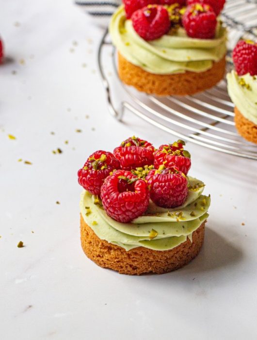 Tartelettes pistache framboise avec crème verte et framboises fraîches sur grille argentée
