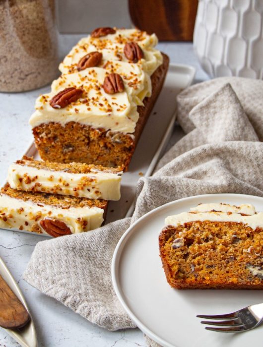 Carrot cake tranché avec glaçage crémeux et noix de pécan sur assiette blanche