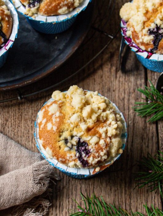 Muffins myrtille dorés avec crumble, présentés sur fond rustique en bois