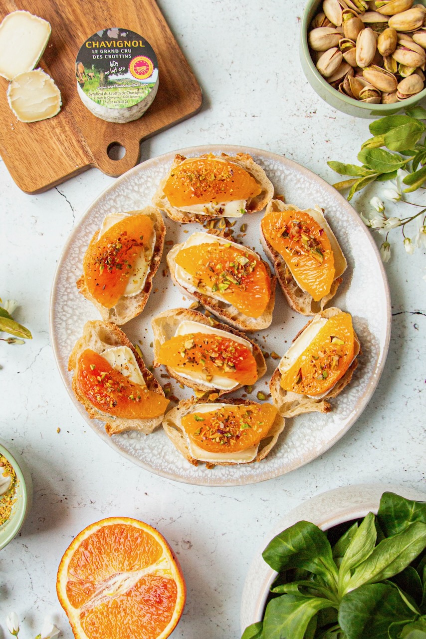 Plate of bruschettas with Crottin de Chavignol, orange segments, and pistachios