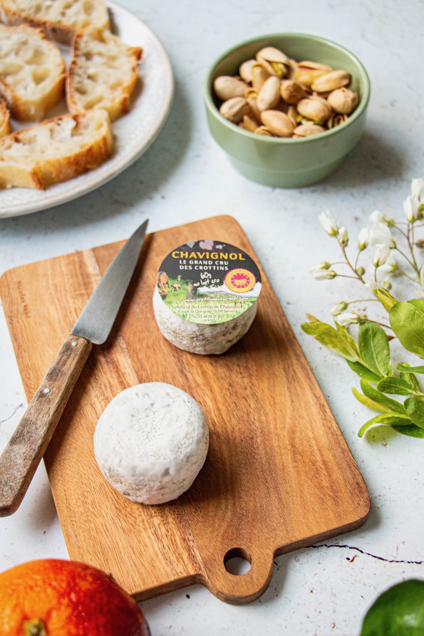 Crottin de Chavignol on a wooden board, with pistachios and sliced bread