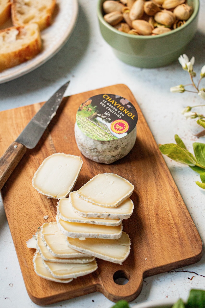 Slices of Crottin de Chavignol on a wooden board, with a knife beside