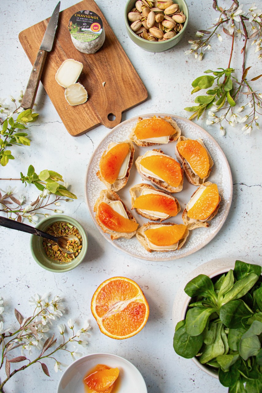 Plate of bruschettas with Crottin de Chavignol, orange segments, and pistachios around