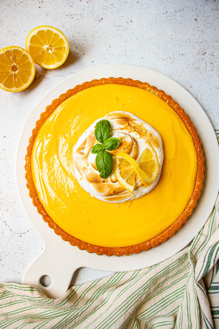 Lemon meringue cake with golden meringue, decorated with lemon slices and basil