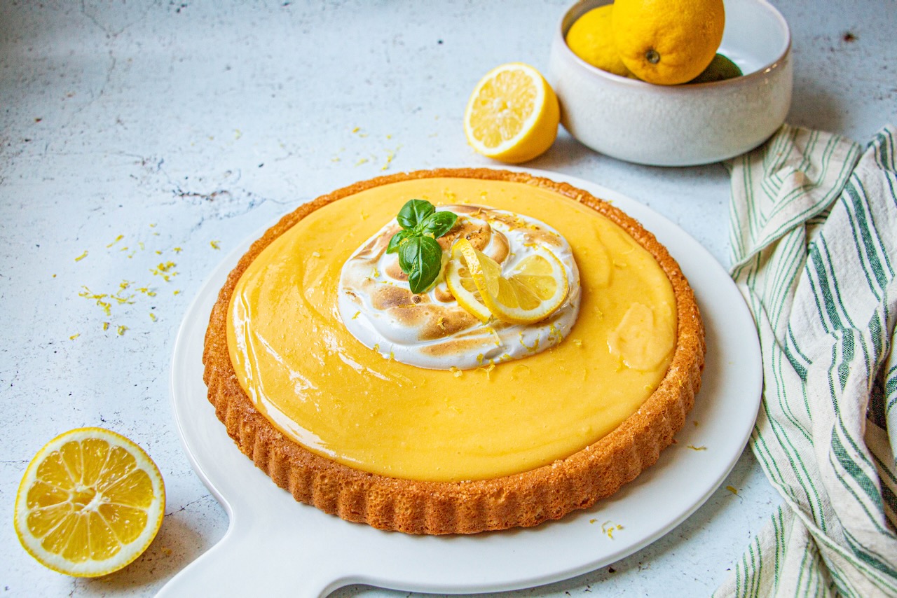 Lemon meringue cake topped with lemon slices and mint leaves