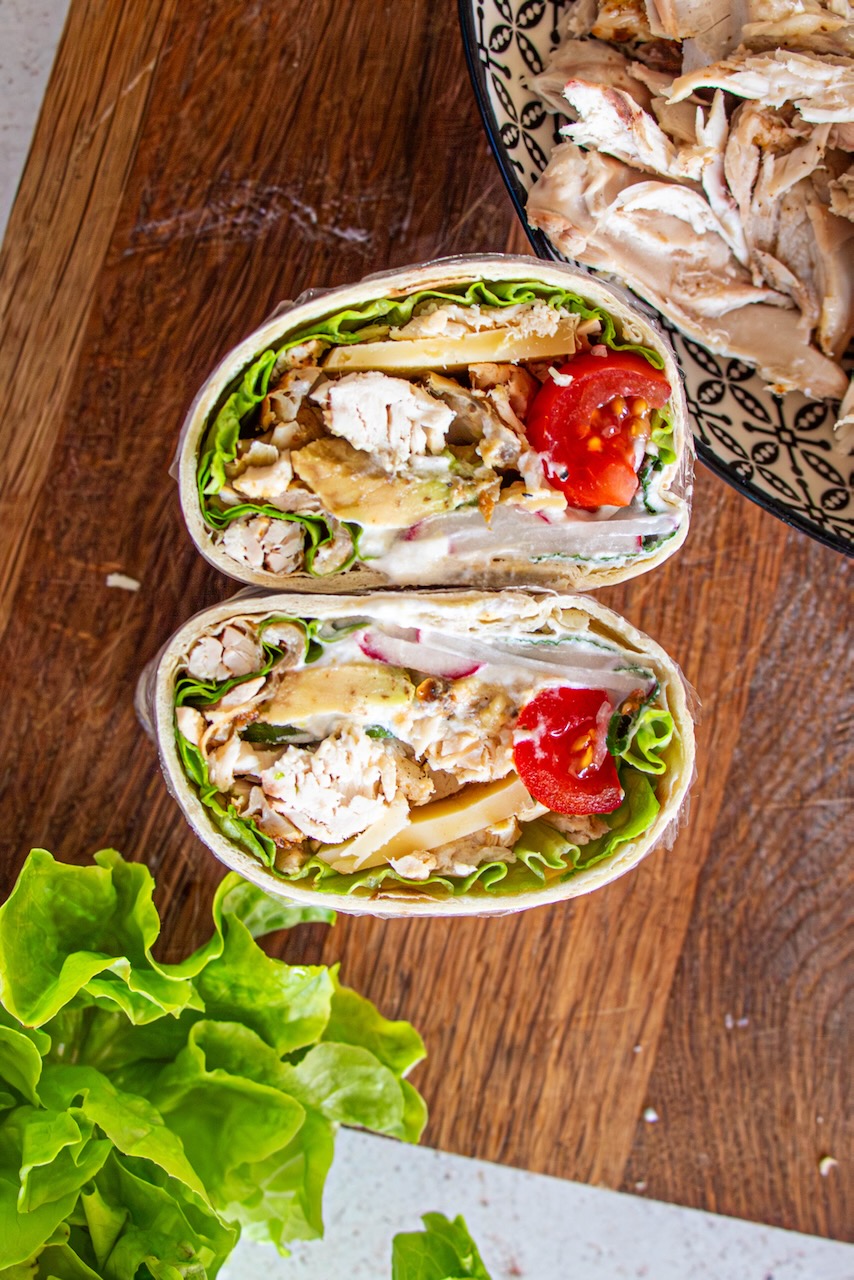 Roasted chicken protein wrap cut in half, filled with lettuce, tomato, and cheese