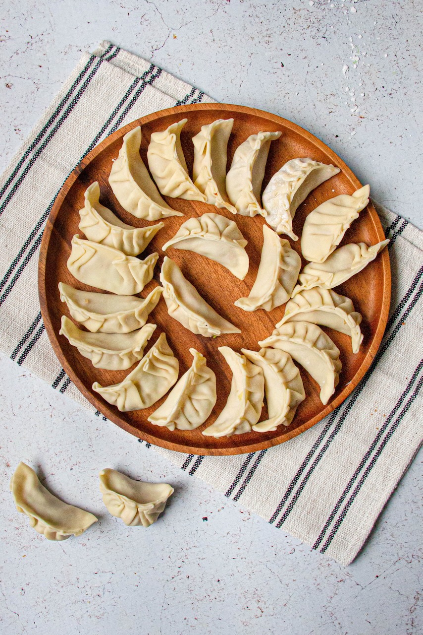 Folded pork gyozas ready to cook on a floured tray